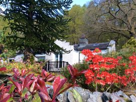 A house with a garden featuring flowers and trees at The Dove Cot in Ambleside