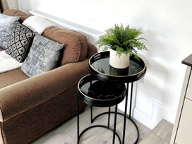 A living room with a sofa, nested tables, and a plant at The Dove Cot in Ambleside