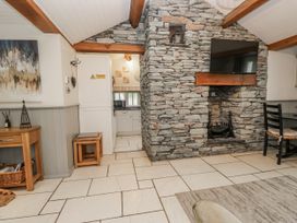A living room with a stone wall and television at The Dove Cot in Ambleside