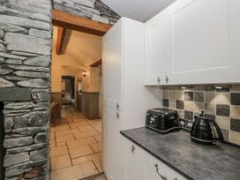 A kitchen with white cabinets and appliances at The Dove Cot in Ambleside