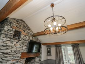 A living room with a stone wall and chandelier at The Dove Cot in Ambleside