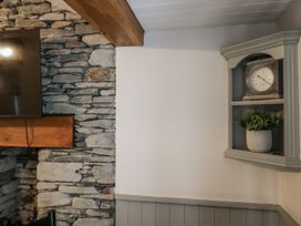 A living room with a stone wall and a clock on a shelf at The Dove Cot in Ambleside
