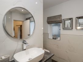 A bathroom with a round mirror and a sink at The Dove Cot in Ambleside