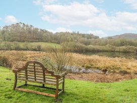 A bench overlooking a water body with trees at The Dove Cot in Ambleside