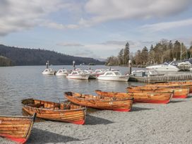 Wooden boats on a gravel shore with motorboats on water at The Dove Cot in Ambleside