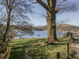 A lake with a boat and trees in the background at The Dove Cot in Ambleside
