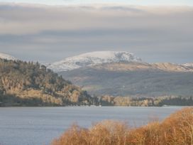 A lake with mountains and trees in the background at The Dove Cot in Ambleside