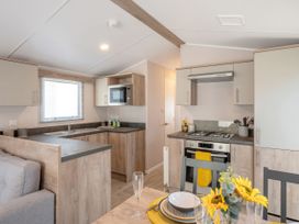 A kitchen with stove, sink, microwave and dining area at 554 Pentreath View, Perranporth