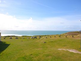 A view of the sea and grass with stones at 554 Pentreath View in Perranporth