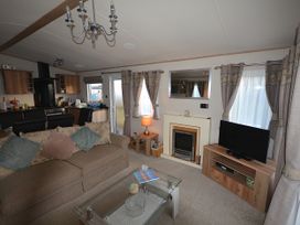 A living room with a sofa, television, coffee table, and fireplace at 457 Pentreath View in Perranporth