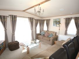 A living room with a sofa and glass table at 457 Pentreath View in Perranporth