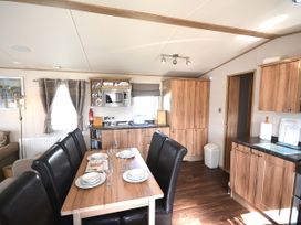A kitchen with table and chairs and cabinets at 457 Pentreath View Perranporth