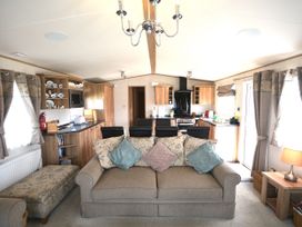 A living room with a sofa and kitchen area at 457 Pentreath View Perranporth