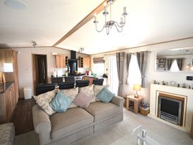 A living room with sofa and kitchen area at 457 Pentreath View in Perranporth