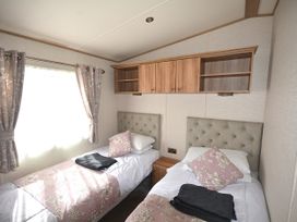 A bedroom with twin beds and a shelf at 457 Pentreath View, Perranporth