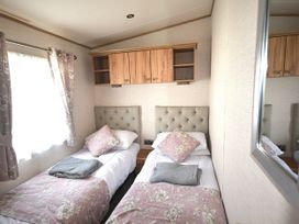 A bedroom with two beds and a shelf at 457 Pentreath View in Perranporth