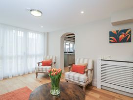 A living room with chairs, a table, and flowers at Paddock View in Stow-On-The-Wold