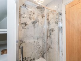 A shower with glass door and marble wall tiles at Paddock View in Stow-On-The-Wold