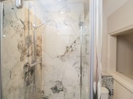 A shower with marble walls and a toilet in Paddock View Stow-On-The-Wold