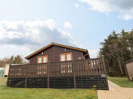 A lodge with a balcony and pathway at Nevaeh Lodge Longframlington