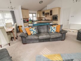 A living room with a sofa and dining area at Nevaeh Lodge Longframlington