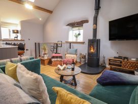 A living room with a wood stove and coffee table at The Old Cartshed | Yr Hen Gwt Cart in Abergele