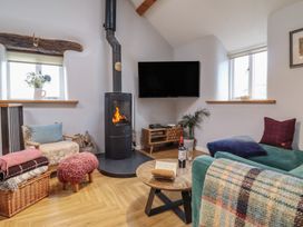 A living room with a wood burning stove and seating area at The Old Cartshed | Yr Hen Gwt Cart in Abergele
