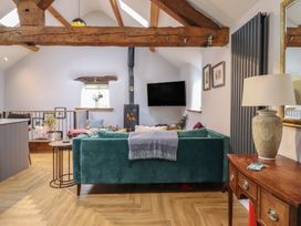 A living room with wooden beams and a television at The Old Cartshed | Yr Hen Gwt Cart in Abergele