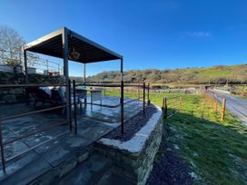 An outdoor area with a pergola and furniture at The Old Cartshed | Yr Hen Gwt Cart in Llangernyw
