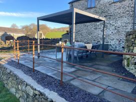 An outdoor area with a pergola and seating at The Old Cartshed | Yr Hen Gwt Cart in Llangernyw
