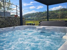 A hot tub and outdoor seating at The Old Cartshed | Yr Hen Gwt Cart in Llangernyw