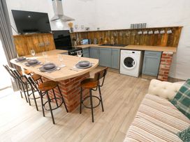 A kitchen with bar stools and appliances at Woodpecker in Haverfordwest