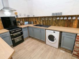 A kitchen with a stove, washing machine, and sink at Woodpecker in Haverfordwest