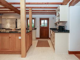 A kitchen with wooden cabinets and a sink at Pylemoor Cottage in Washfield near Tiverton