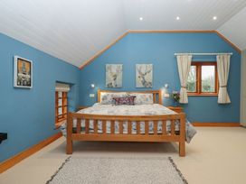 A bedroom with a bed and paintings at Pylemoor Cottage in Washfield near Tiverton