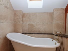 A bathroom with a bathtub and tile walls at Pylemoor Cottage Washfield near Tiverton