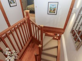 A staircase with wooden handrail in a hallway at Pylemoor Cottage in Washfield near Tiverton
