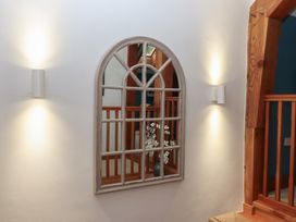 A mirror and light fixtures on the wall in a hallway at Pylemoor Cottage near Tiverton