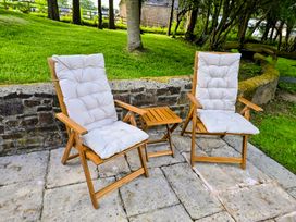 A patio with two reclining chairs and a small table at Pylemoor Cottage Washfield near Tiverton