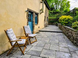 An outdoor area with wooden chairs and a stone pathway at Pylemoor Cottage in Washfield near Tiverton