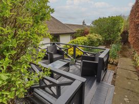 A deck with chairs and a table surrounded by greenery at Tigh-Na-Mara Retreat
