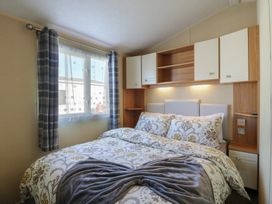 A bedroom with a bed and shelves at Ocean Breeze Escape Allhallows