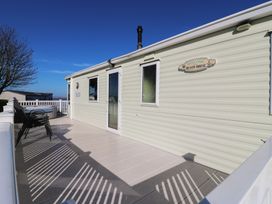 An outdoor deck with chairs at Ocean Breeze Escape in Allhallows