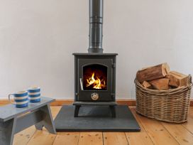 A living room with a wood stove and mugs at The Old Studio in Penzance