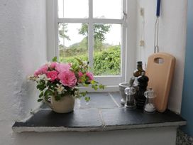 A kitchen window with a flower vase and various kitchen items at The Old Studio in Penzance