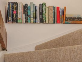 A staircase with a shelf of books at The Old Studio in Penzance
