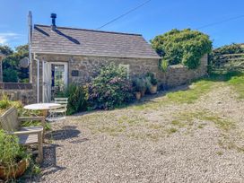 An outdoor area with a table and chairs beside a stone building at The Old Studio in Penzance