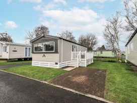 A park home with a decking area and grass at Hadrian's Rest in Wigton
