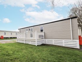 A mobile home with a deck in an outdoor area at Hadrian's Rest in Wigton