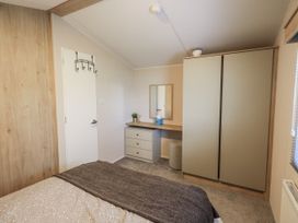 A bedroom with a bed, desk, and storage at Hadrian's Rest in Wigton